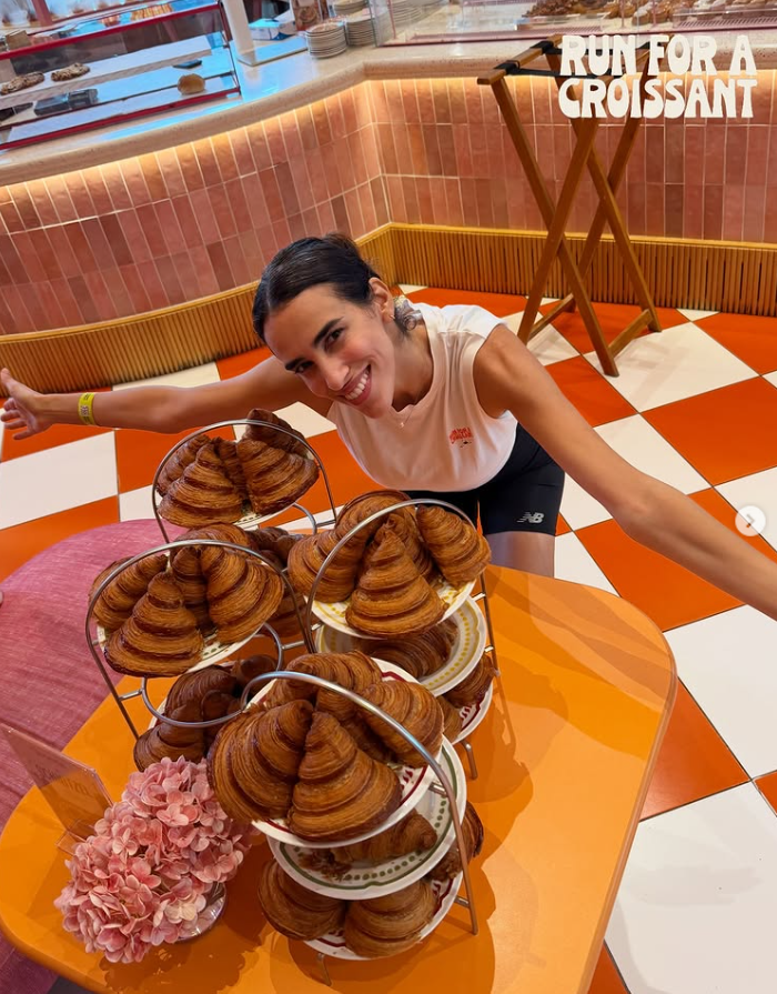 Croissant Run Club member celebrating beside trays of fresh croissants